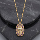 INRI Crucifix Purple Channel Crystal Oval Pendant Necklace on a dark stone surface