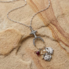 Multiple charm cross pendant necklace resting on a brown sandstone surface