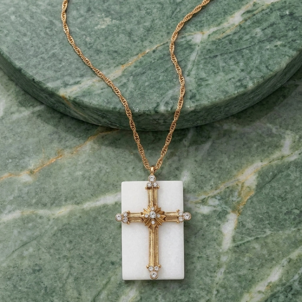 Gold cross pendant necklace on a green stone background