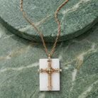 Gold cross pendant necklace on a green stone background