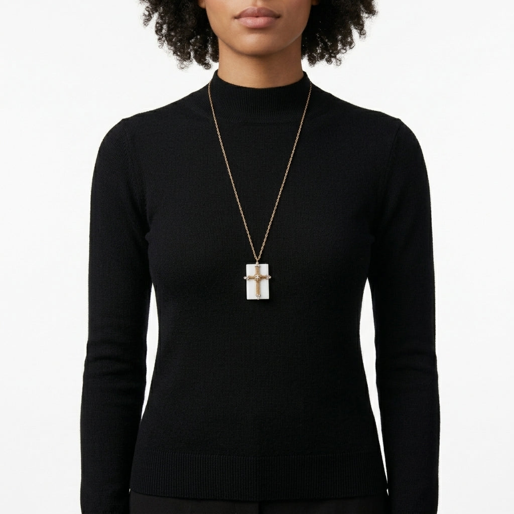 Person wearing a black turtleneck and a necklace with a square cross pendant on a white background