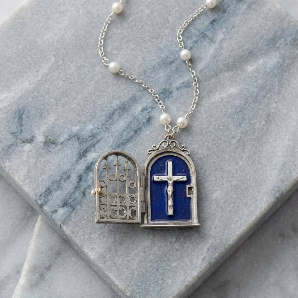 Necklace with a blue enamel cross locket featuring a crucifix on a marble surface