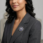 Woman wearing a gray blazer with a decorative Star of Bethlehem brooch on a neutral background