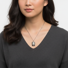 Woman wearing a necklace with a radiant cross star pendant against a neutral background