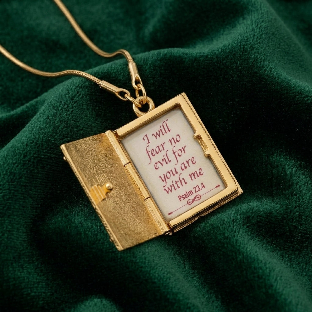 Gold necklace with an opened Bible pendant displaying a religious quote from Psalm 23:4 on a green fabric background