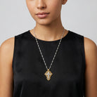 Woman wearing a cross crucifix pendant necklace with a silver tone chain and gold tone accents