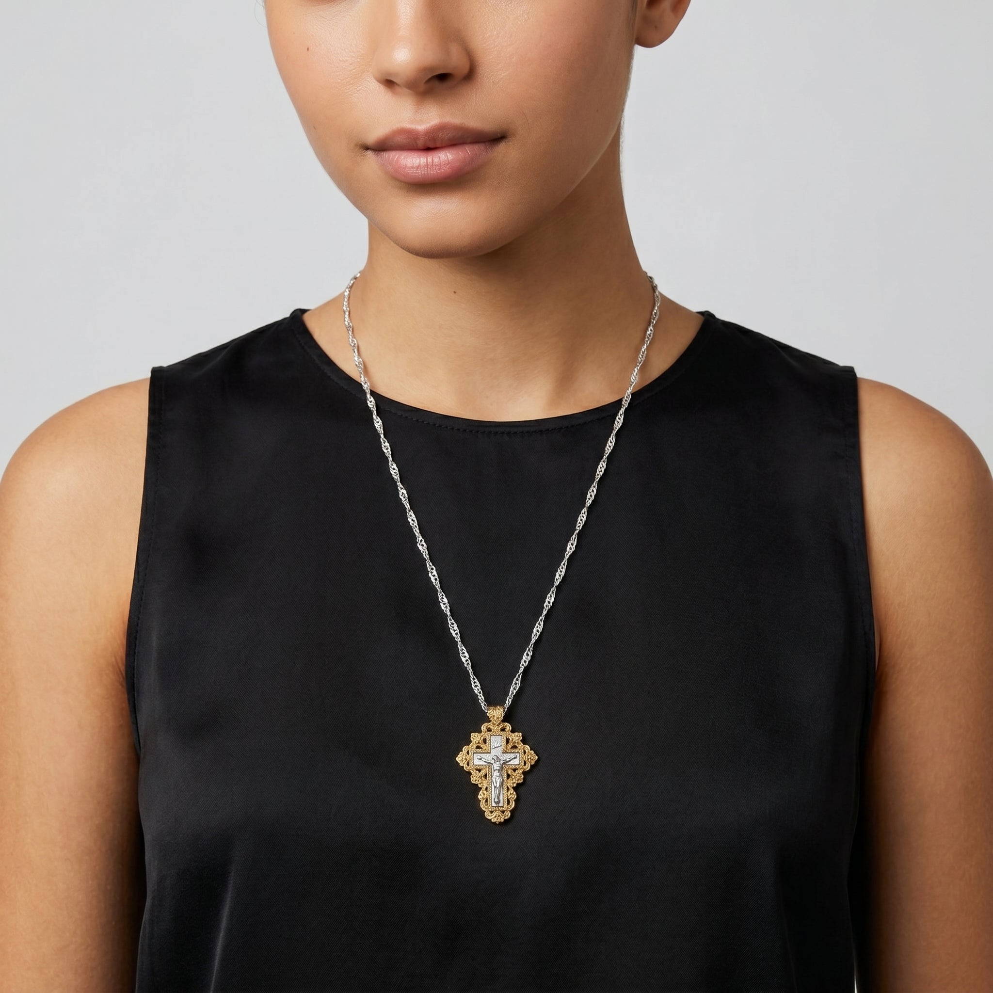 Woman wearing a cross crucifix pendant necklace with a silver tone chain and gold tone accents
