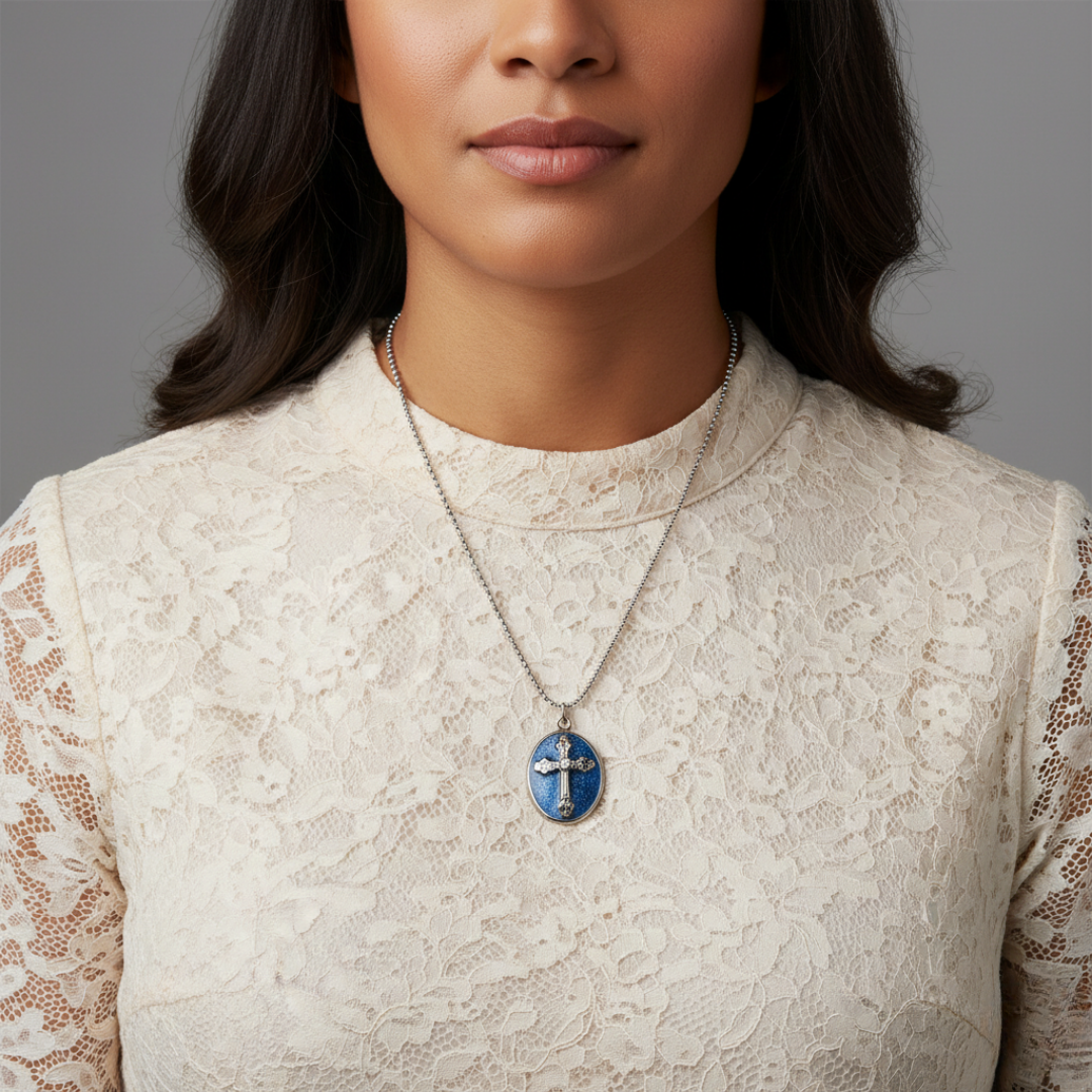 Woman wearing a necklace with a blue cross pendant against a gray background