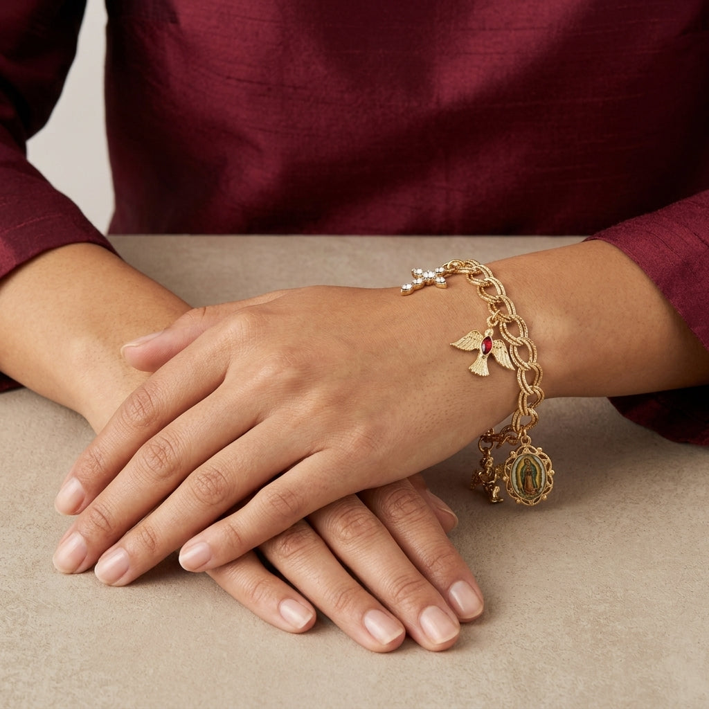 Gold bracelet with religious charms on a hand against a neutral background