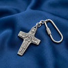 Silver cross keychain with carabiner on a blue fabric background