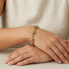 Gold bracelet with religious charms on a person's wrist with a neutral background