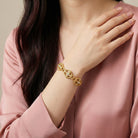Woman wearing a gold bracelet with AB crystals on a neutral background