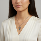 Woman wearing a necklace with a cross pendant on a plain background
