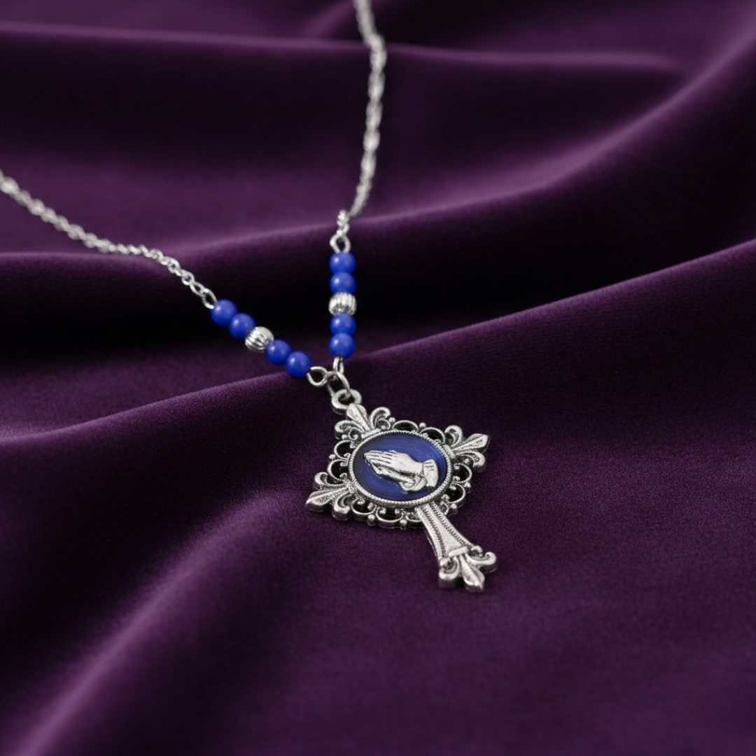 Necklace with a silver cross pendant and blue beads on a purple fabric background