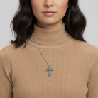 Woman wearing a beige turtleneck sweater with a silver necklace featuring a blue pendant.