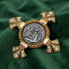 Decorative religious brooch with gold and silver design on a green fabric background