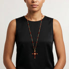 Woman wearing a siam Red crystal cross necklace with red beads on a gold tone chain