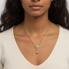 Woman wearing a gold necklace with a heart-shaped pendant against a neutral background