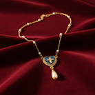 Gold necklace with a heart-shaped pendant featuring a cross on a red fabric background.