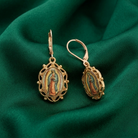 Gold earrings with religious design on a green fabric background