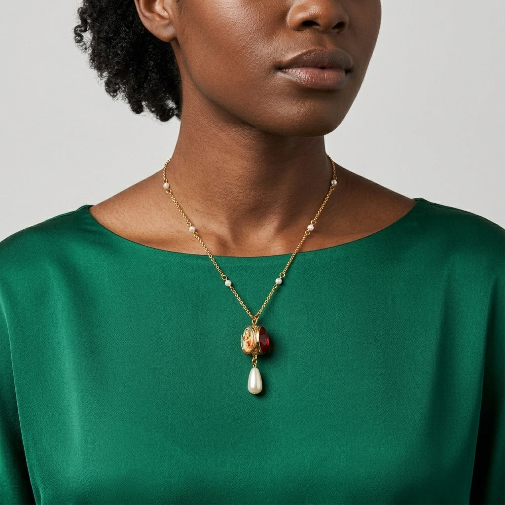 Woman wearing a gold necklace that has faux pearl accents with a Mother Mary spinner pendant against a neutral background