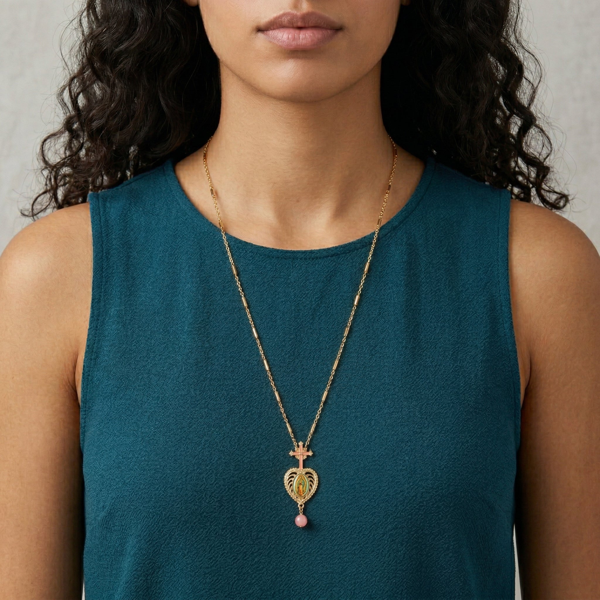 Woman wearing a gold necklace with a heart-shaped pendant on a plain background