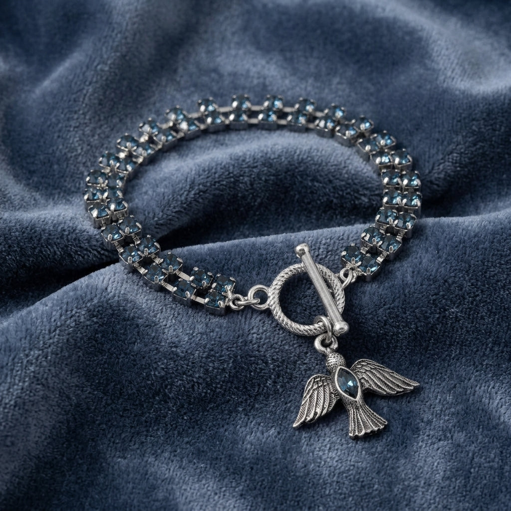 Silver bracelet with angel wing charm on a blue fabric background