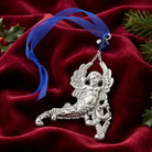 Silver tone winged cherub ornament with a blue ribbon an blue crystal on a red fabric background
