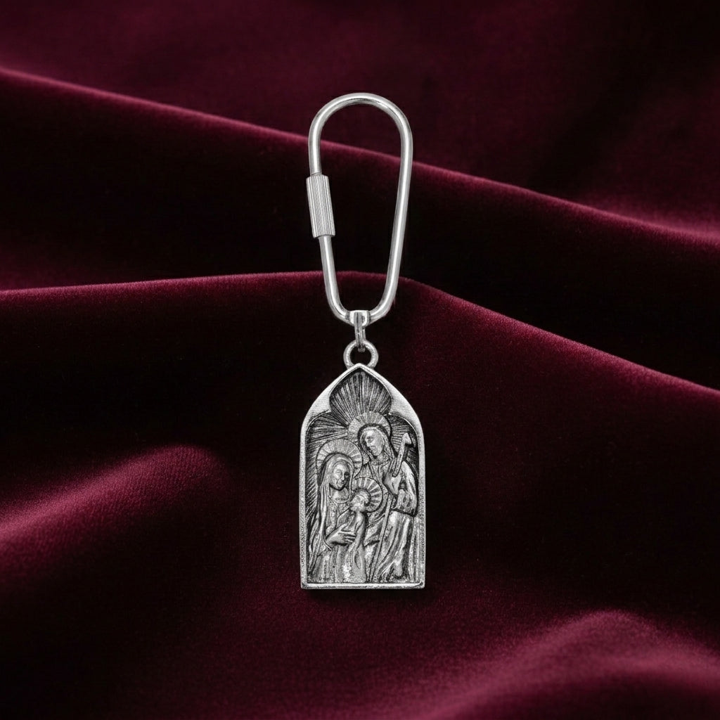Silver keychain with religious design on a maroon fabric background