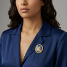 Woman wearing a blue blazer with a gold and blue religious brooch on a gray background