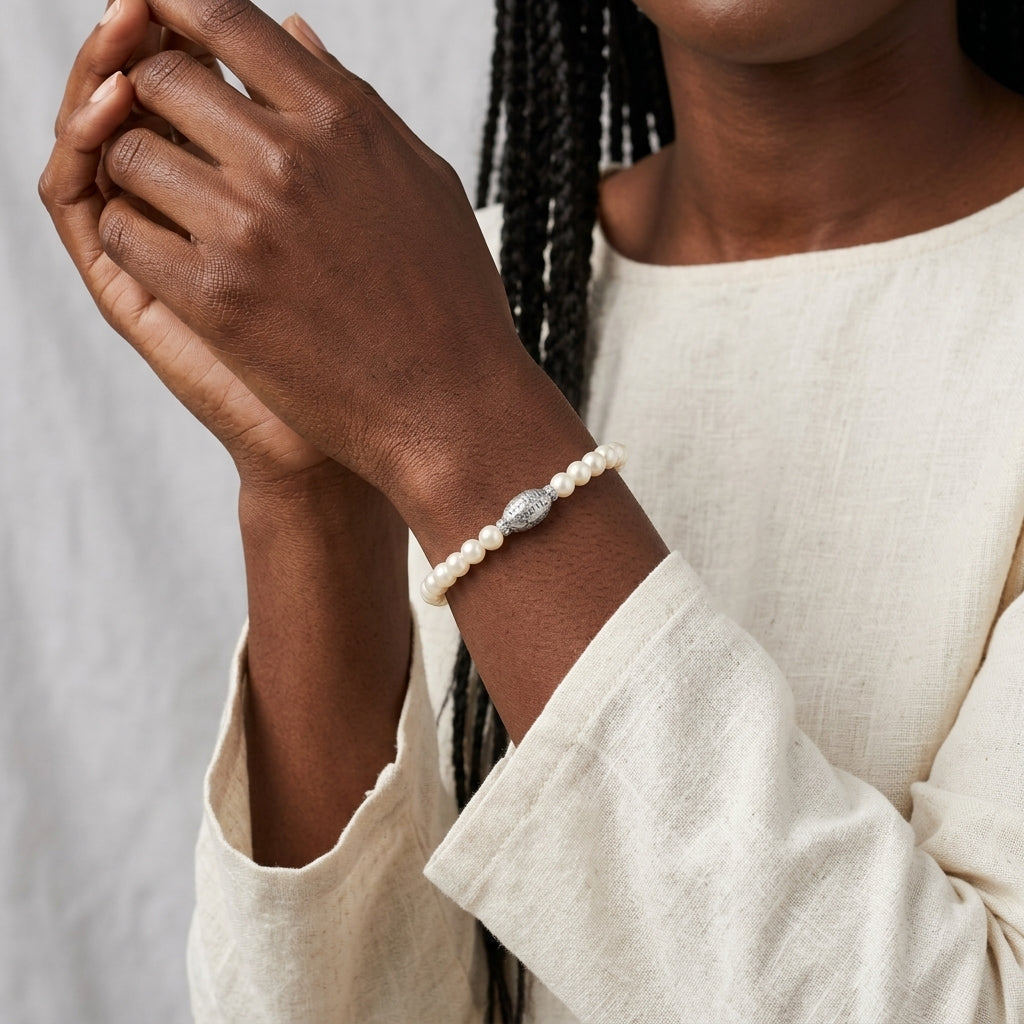 Person wearing a pearl bracelet on a plain background