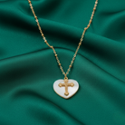 Necklace with a heart-shaped pendant featuring a cross on a green fabric background