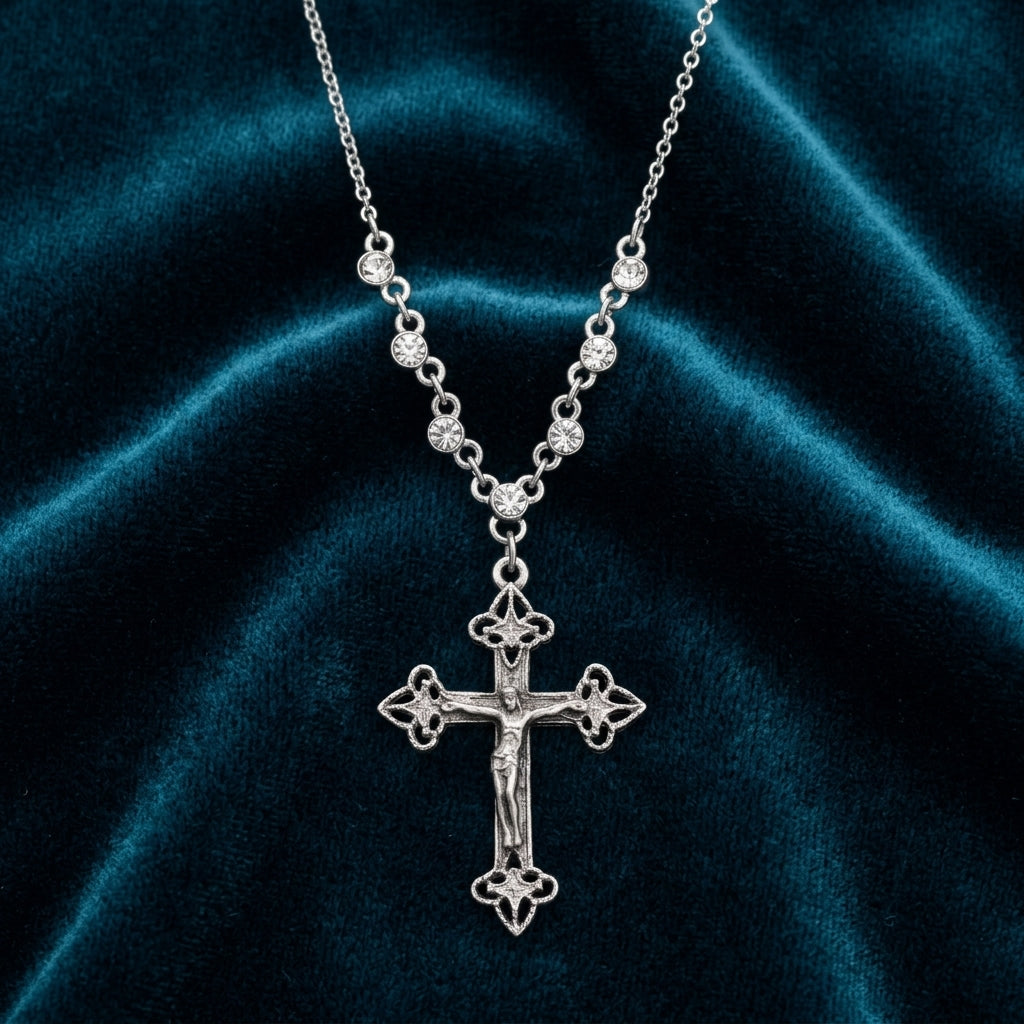 Silver cross necklace with clear crystal accents on a dark blue velvet background