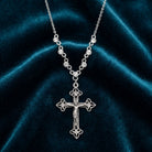 Silver cross necklace with clear crystal accents on a dark blue velvet background