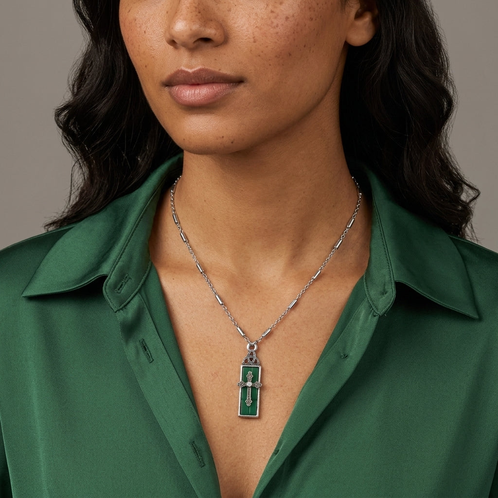 Person wearing a green shirt and silver necklace with a cross pendant