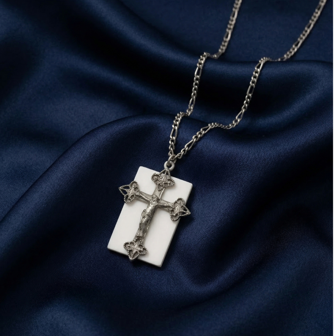 Silver cross pendant necklace on a dark blue fabric background