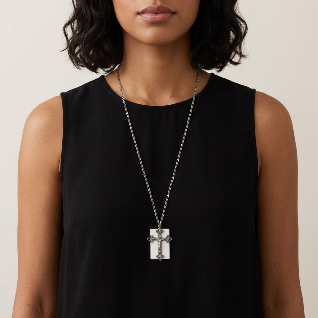 Woman wearing a black sleeveless top with a silver necklace featuring a cross pendant.