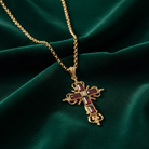 Gold cross pendant necklace on a green fabric background