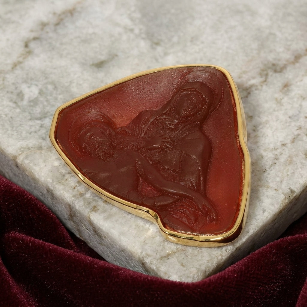 Brooch pin set in carnelian red stone depicting Mother Mary and Jesus on a marble surface
