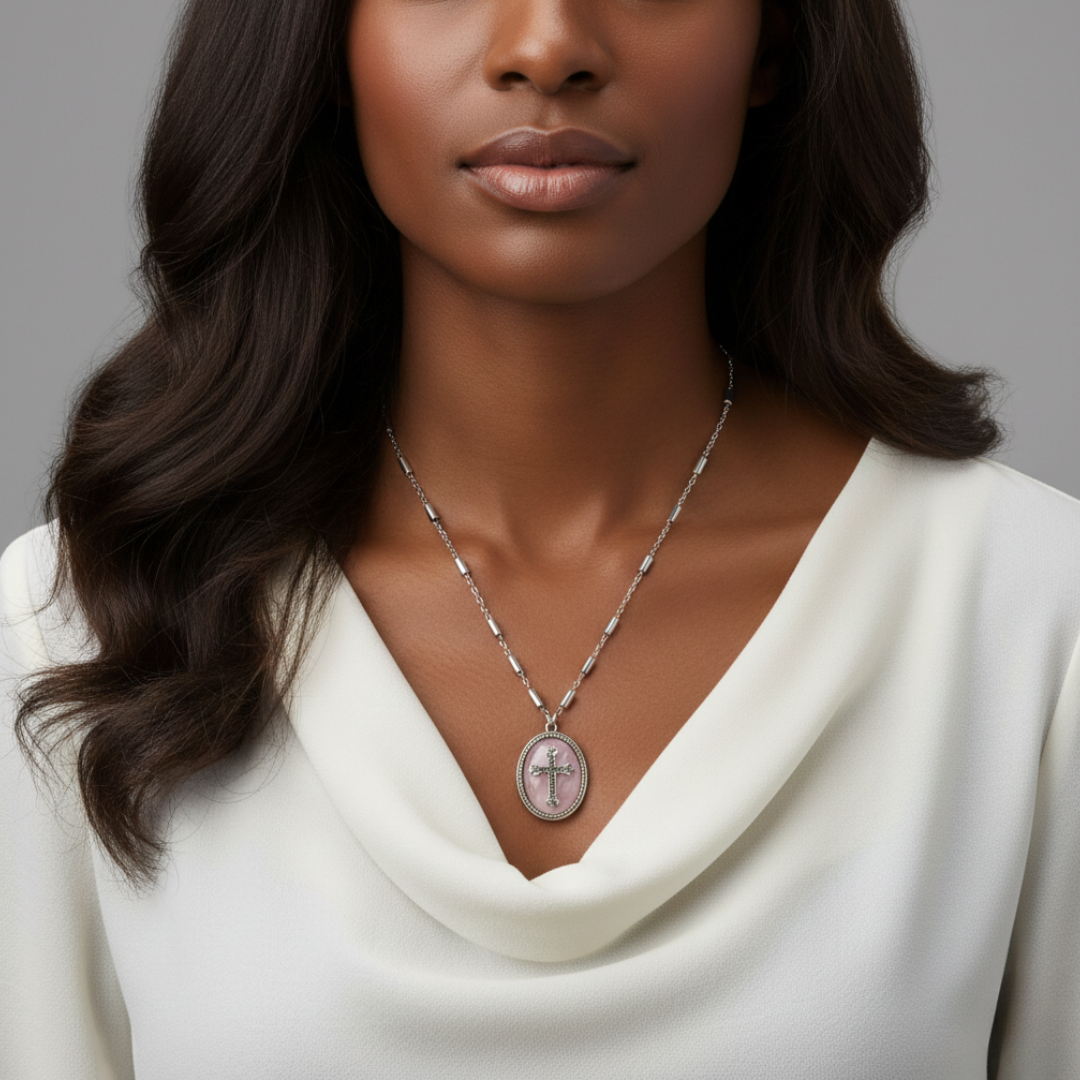 Woman wearing a silver necklace with a cross pendant against a gray background