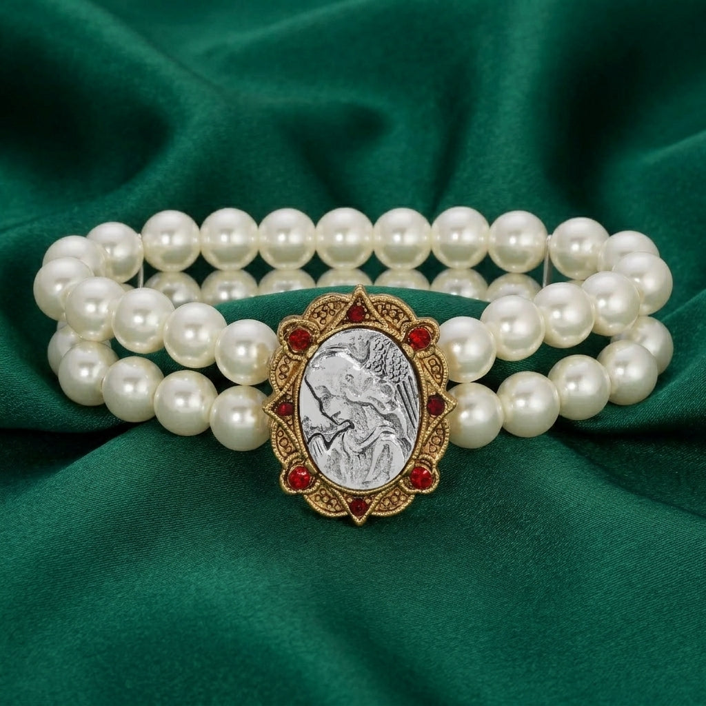 Pearl bracelet with a decorative Guardian Angel design and red crystals on a green fabric background