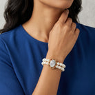 Woman wearing a pearl religious bracelet and red crystals with a blue top