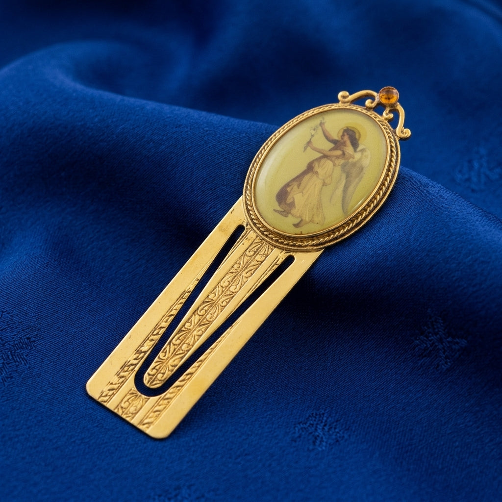 Gold bookmark with a religious angel design on a blue fabric background