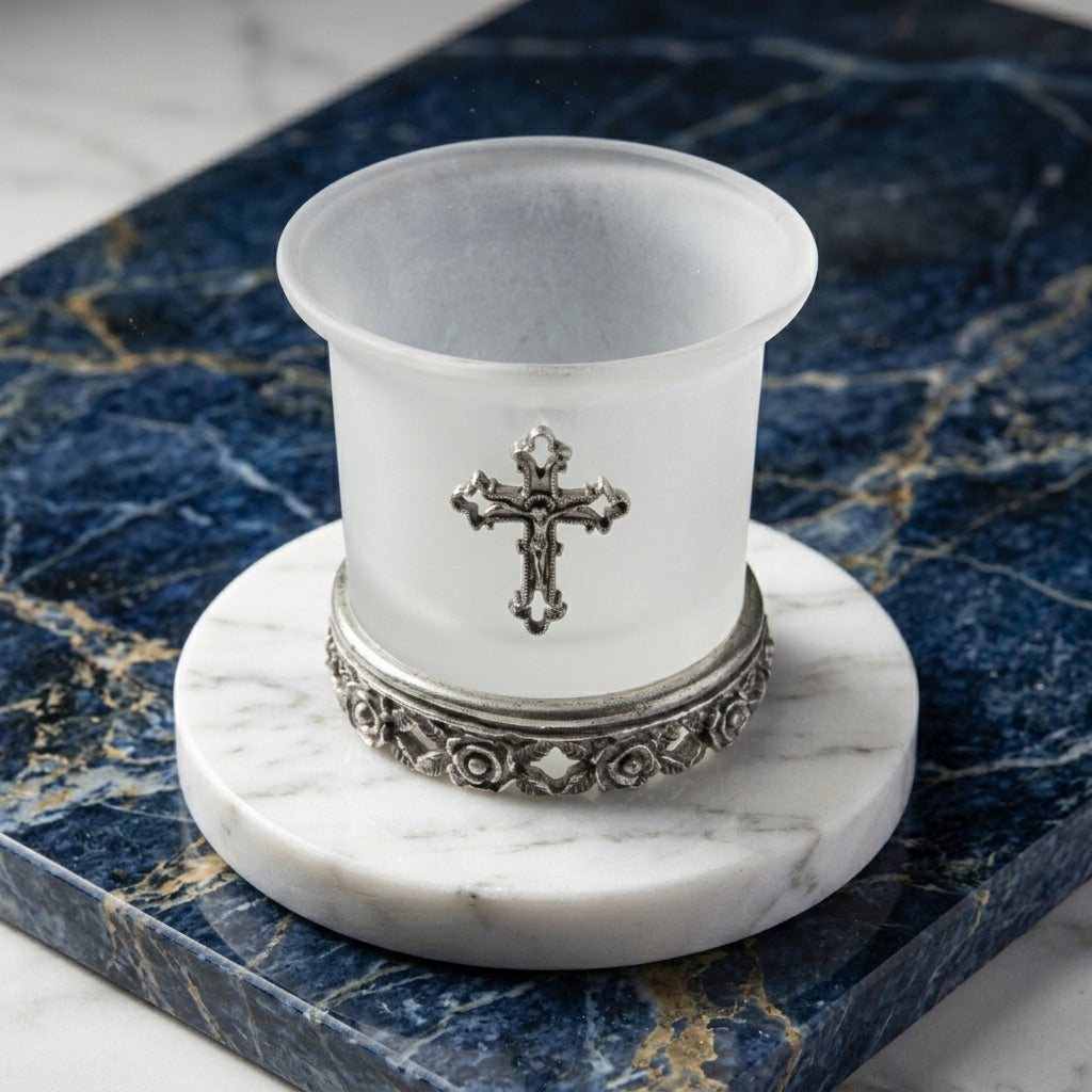 White candle holder with a silver cross design on a blue marble surface