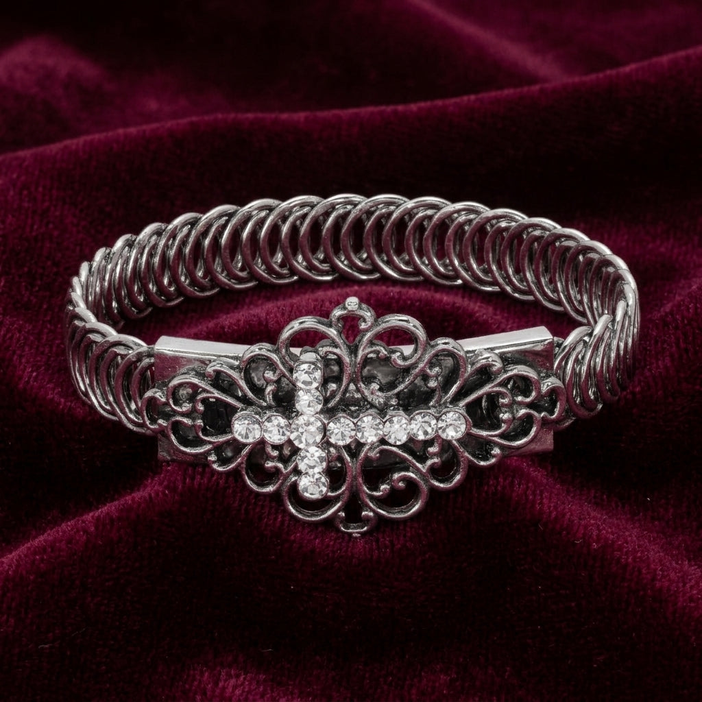 Silver bracelet with crystal accents and a decorative clasp on a burgundy fabric background