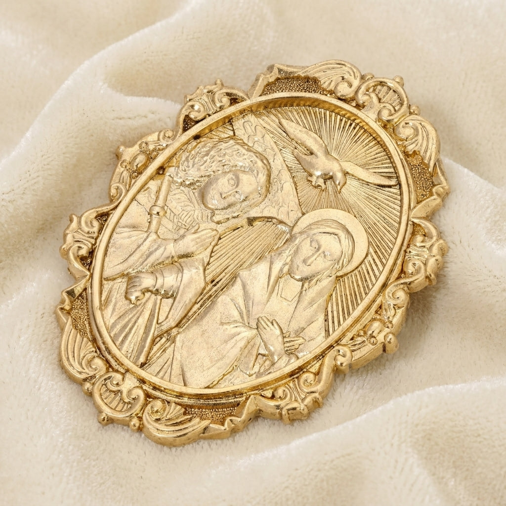 Gold religious brooch with intricate design on a beige fabric background