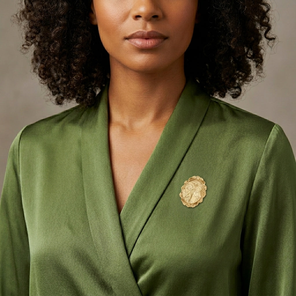 Woman wearing a green satin blouse with a gold religious brooch on a neutral background