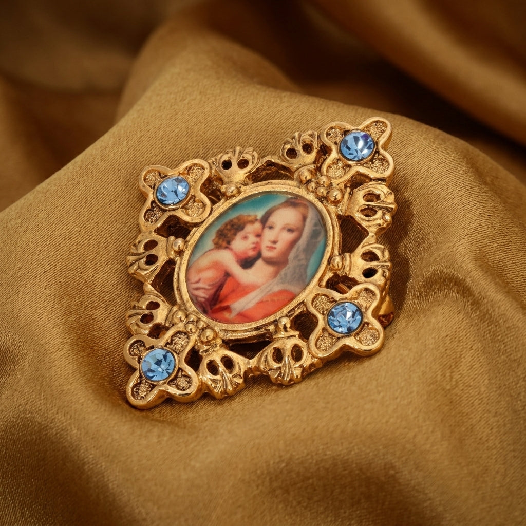 Decorative brooch with Mary and Child portrait and blue crystals on a brown fabric background