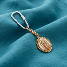 Decorative keychain with Our Lady of Guadalupe design on a blue fabric background