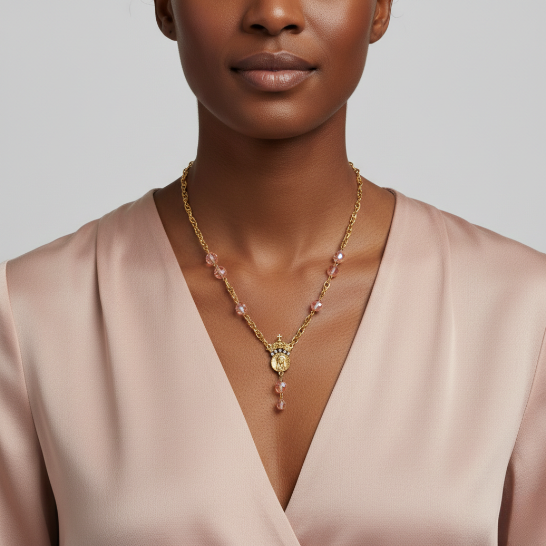Woman wearing a gold necklace with pink beads against a neutral background. 